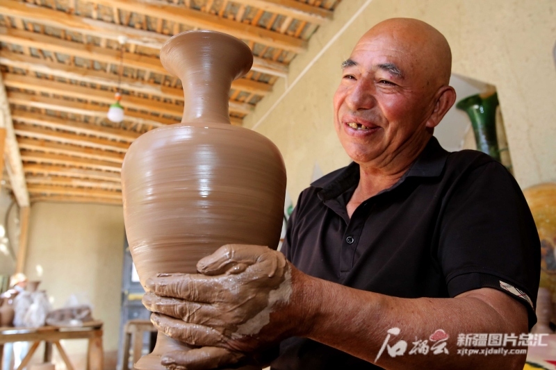 6月19日，英吉沙縣芒辛鎮(zhèn)恰克日庫依村土陶非遺傳承人阿卜杜熱合曼·麥麥提敏在欣賞剛制作的土陶作品,。石榴云/新疆日報記者 蔡增樂 攝